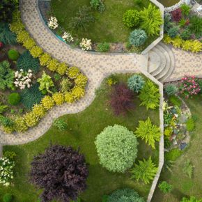 Photo taken from above by flying drone of a very well landscaped yard with walkways, trees, and shrubs