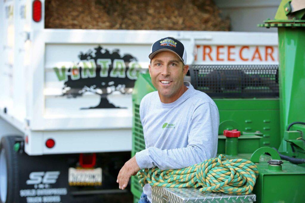 Fred Frey of Vintage Tree Care posing in front of a commercial wood chipper
